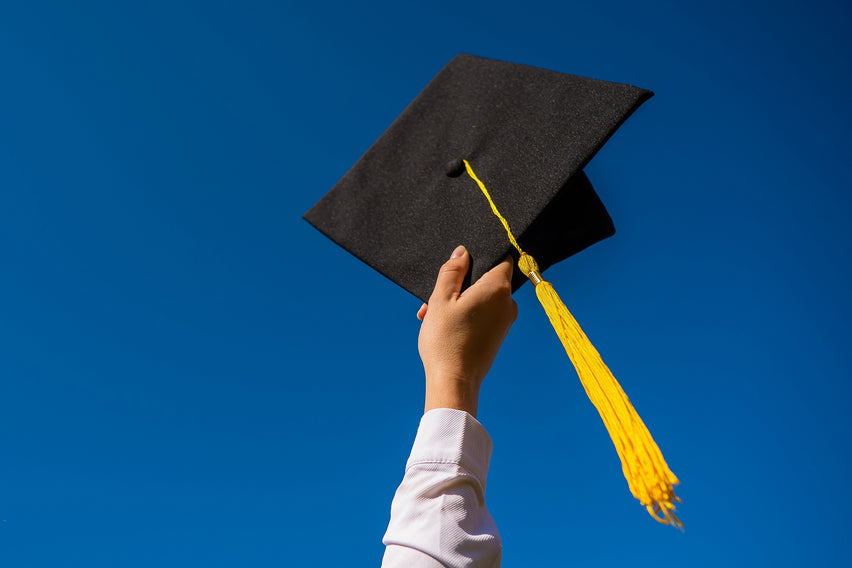Graduation Cap held to the Sky